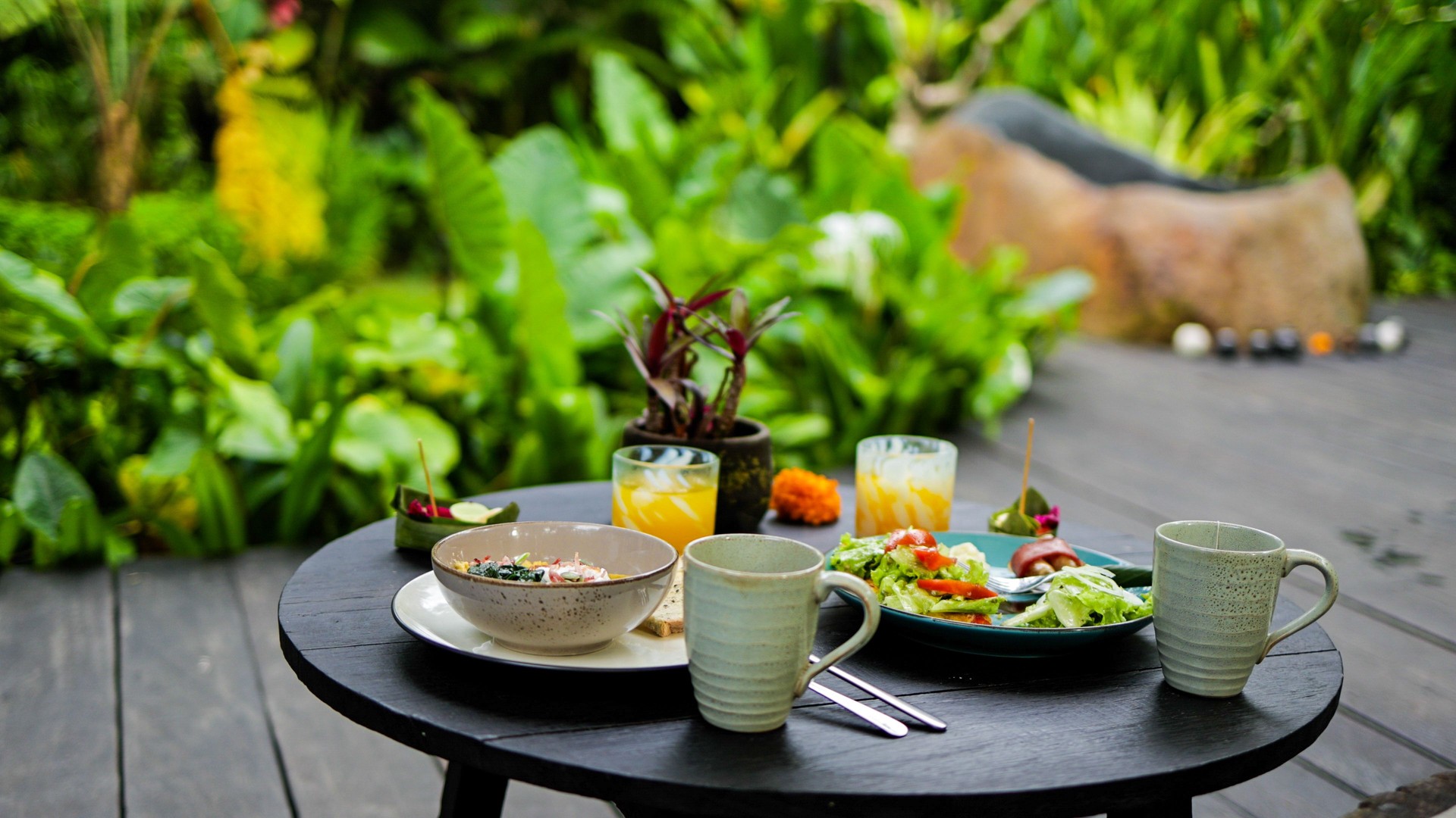 Healthy Breakfast in a Tropical Garden, Bali, Indonesia: Fresh Juices, Nutritious Salad, and Organic Food on an Elegant Outdoor Table, Surrounded by Lush Greenery, Ideal for Promoting Wellness, Mindful Eating, and a Relaxing Tropical Lifestyle
